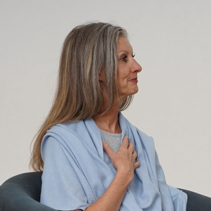 Frau sitzt in Sessel, Hand auf der Brust