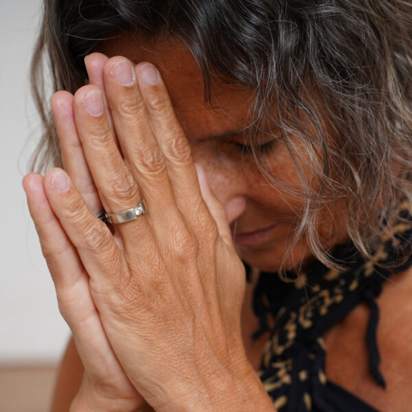 Frau faltet Hände vor ihrem Gesicht zusammen