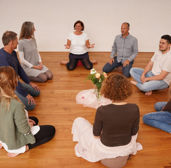 Menschen die im Seminar im Kreis auf dem Boden sitzen