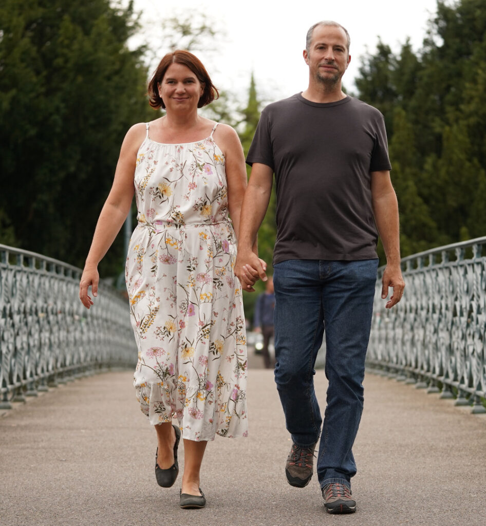 Frau und Mann laufen Hand in Hand über eine Brücke