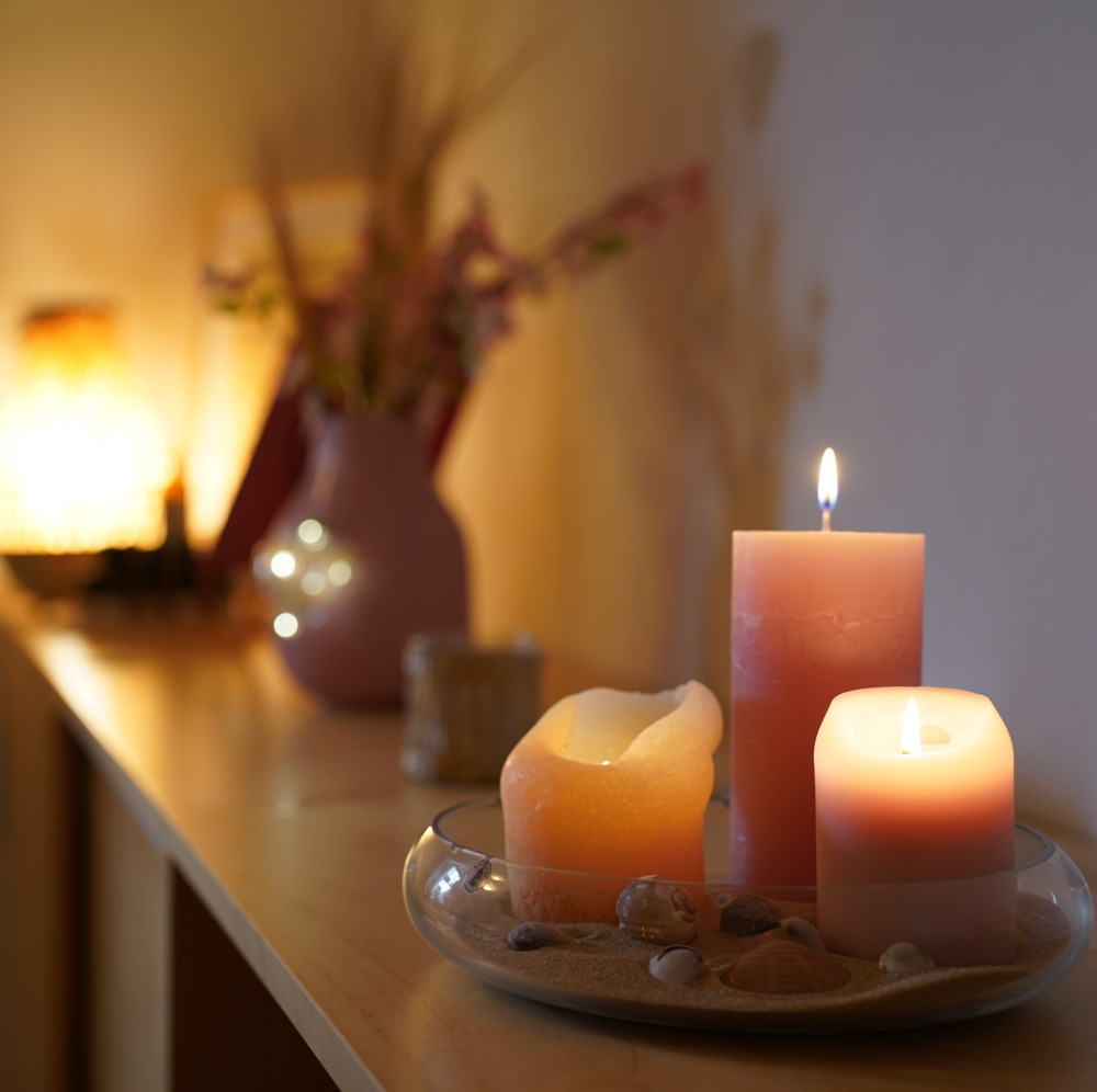 Kerzen auf Sideboard mit Lampe im Hintergrund